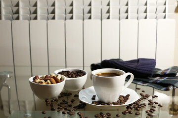 Cup of coffee and coffee beans on a glass table. The concept of home comfort and warmth.