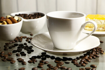 Cup of coffee and coffee beans on a glass table. The concept of home comfort and warmth.