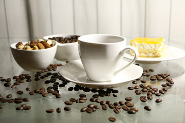 Cup of coffee and coffee beans on a glass table. The concept of home comfort and warmth.
