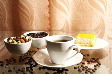 Cup of coffee and coffee beans on a glass table. The concept of home comfort and warmth.