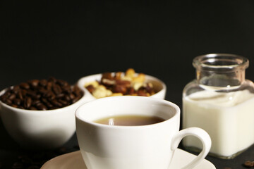 A cup of coffee with milk and coffee beans on a glass table. The concept of home comfort and warmth.