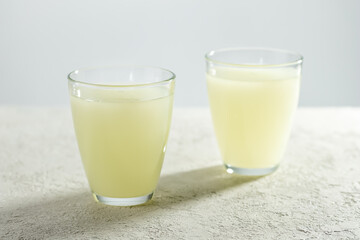 Two glasses of natural whey on a white table