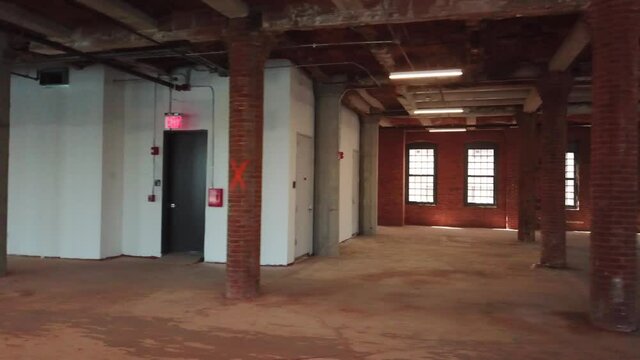 Interior view of an empty, unfinished office space that is under construction inside a large brick building.