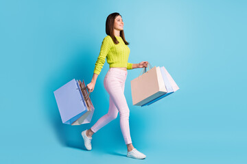 Photo portrait full body view of woman walking with shopping bags isolated on pastel blue colored...