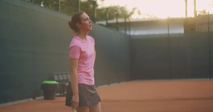 Concentration before the last decisive serve. A woman on a tennis court in slow motion and sunlight