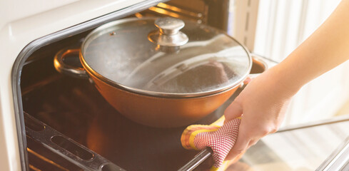 close up woman hands open the oven and take out fresh cooked food at home