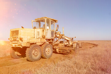 Obraz premium grader machine making a new road, dig the gravel dirt in the field