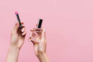 cropped view of woman holding lipstick and bottle with perfume isolated on pink - obrazy, fototapety, plakaty