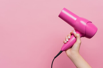 cropped view of woman holding hair dryer isolated on pink - obrazy, fototapety, plakaty