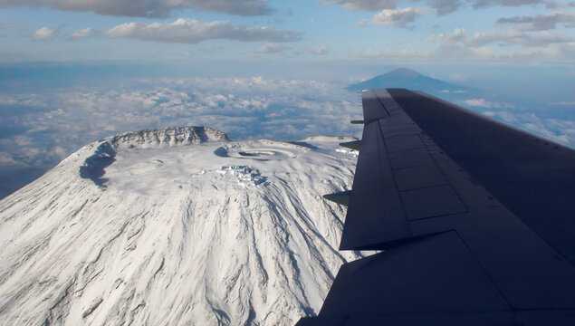 Aerial view from an airplane of the summit of Kibo, the highest point on Kilimanjaro. The volcano is completely covered with snow and ice. Mt. Meru is out of focus on the horizon.