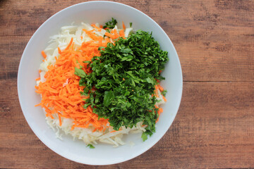 Salad with carrot and cabbage with parsley. Fresh vegetable ingredients in a bowl. 