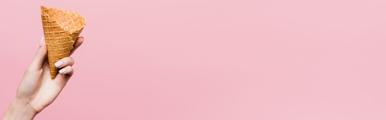 cropped view of woman holding waffle cone isolated on pink, banner