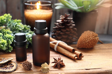 natural essential oil bottles are on the wooden table with cinnamon sticks, star anise, pinecone and potpourri with background of scented candles and wooden wall decorate in the living room