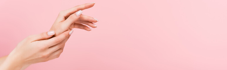 partial view of woman applying cosmetic cream on hands isolated on pink, banner