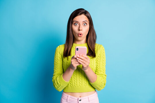 Photo of young girl amazed shocked surprised fake novelty news rumor chat mobile cellphone isolated over blue color background