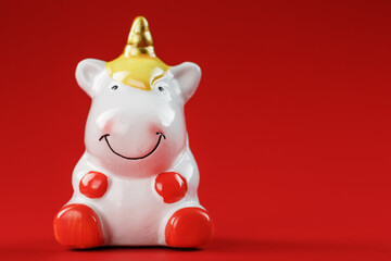 Unicorn figurine on a red background with free space.