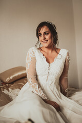 Fototapeta premium Happy bride sitting with bouquet on bed