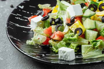 Greek Salad with Cucumeber, Kalamata Olives, Feta Cheese, Juicy Cherry Tomatoes and Fresh Basil. Concept for a tasty and healthy vegetarian meal