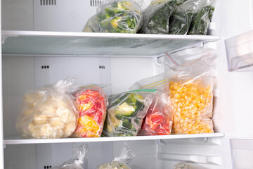 Plastic bags with deep frozen vegetables in refrigerator, closeup