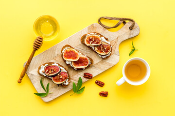 Sandwiches with cheese, fresh figs and walnuts on wooden cutting board