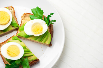 Toast with avocado and egg on white plate. Top view. Healthy breakfast