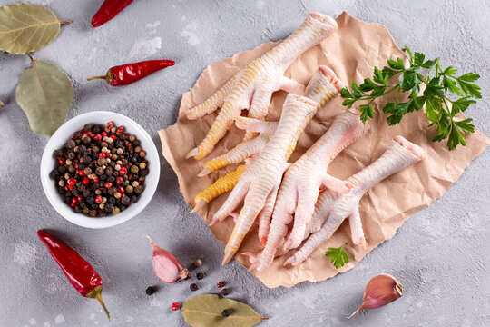 Raw chicken feet with herbs and vegetables on gray background. Natural collagen of animal origin