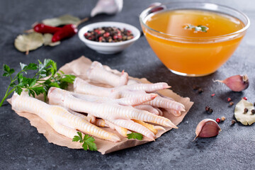 Chicken broth and chicken feet with vegetables, spices and herbs on gray background. Natural collagen