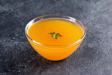 Broth in small glass bowl on dark gray background