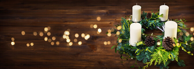 Advent wreath on dark wooden table with golden bokeh lights and christmas mood. Horizontal...