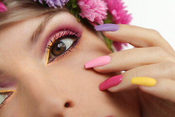 Fashionable multi-colored makeup and manicure on long nails of a girl with asters .