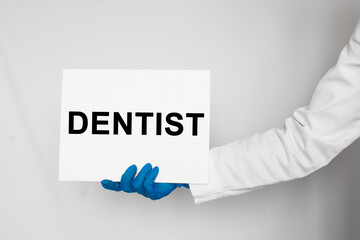 The doctor's blue - gloved hands show the word DENTIST - . a gloved hand on a white background. Medical concept. the medicine