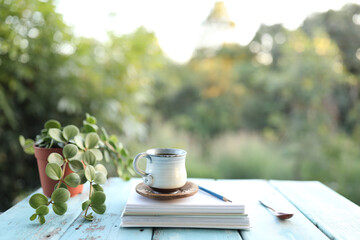 Vintage old coffee cup and notebook with plant pot on wooden table
