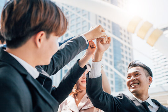Asian business people joining hands together.