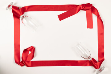 two glasses wrapped in a red satin ribbon lie on a white background