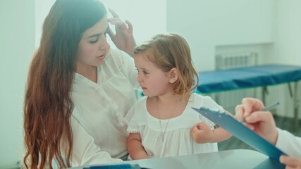 Female Doctor Pediatrician Examining an Ill Sad Kid Girl at Medical Visit With Mother in the Hospital. Female Family Doctor Examining and Consulting to Mother and Her Crying Child.