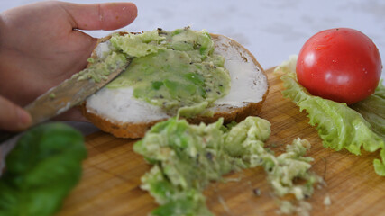Spreading Mashed Avocado On a Toast. Healthy Vegan Breakfast. Cooking healthy food
