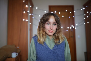 The girl smiles. Christmas mood. New Year. The girl smiles and rejoices in the New Year. Close-up portrait. Wavy hair.
