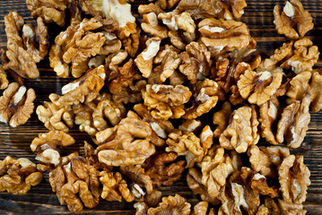 Walnut texture close up. Many halves of peeled nuts on an old wooden board. Food on a background of shabby brown board.