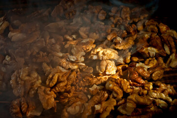 Walnut texture close up. Many halves of peeled nuts on an old wooden board. Food on a background of shabby brown board. Contrasting dramatic light as an artistic effect.
