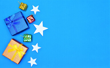 Blue background with Christmas decoration, stars and gifts. Space for text or idea.