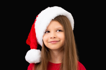 A cute little girl in a Christmas hat is smiling.