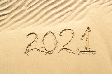 Numbers 2021 new year are written in the sand. Wawy sand on the beach.