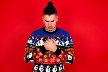 Sad Young handsome Caucasian man wearing Christmas sweater against red desperate and depressed with tears on her eyes suffering pain and depression  in sadness facial expression and emotion concept