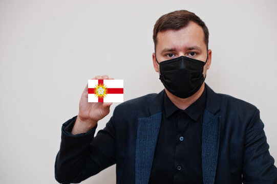 Man wear black formal and protect face mask, hold West Riding of Yorkshire flag card isolated on white background. United Kingdom counties of England coronavirus Covid concept.