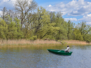 A fisherman catches fish in early spring against the backdrop of trees.