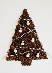 Christmas tree made of coffee beans decorated with silver balls and beads. On white background isolated
