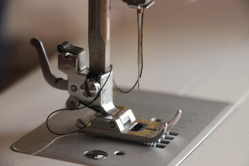 Presser foot of sewing machine threading the textile macro close up. Manufacture business concept