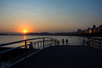 Sunset view at Santos beach, Canal 6, bridge and buildings on the waterfront.