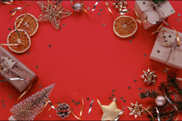 Christmas decorations, gift boxes, dried orange slices, baubles on red background with copy space