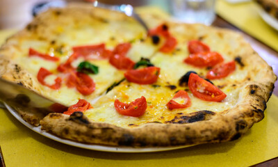 Eating of Italian pizza with mozzarella cheese, small red tomatoes and fresh basil